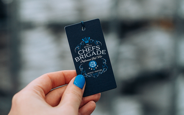Hand holding a 'Chefs Brigade' card with a blurred background