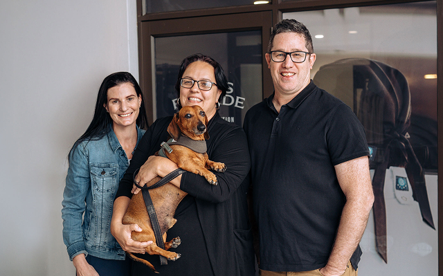 Three people and a dog smiling for the camera