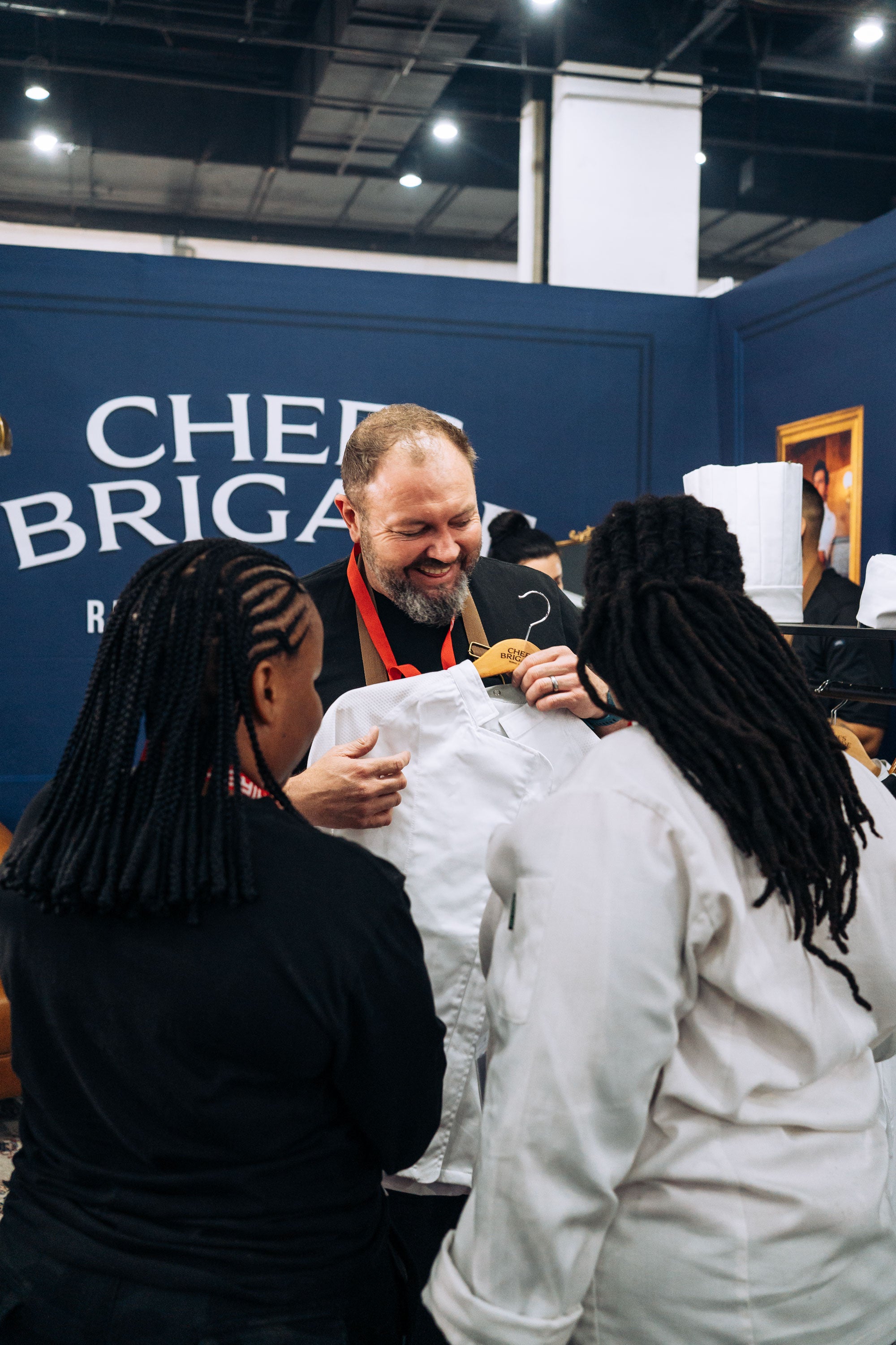 Man interacting with two people in front of a 'Chief Brigade' sign.
