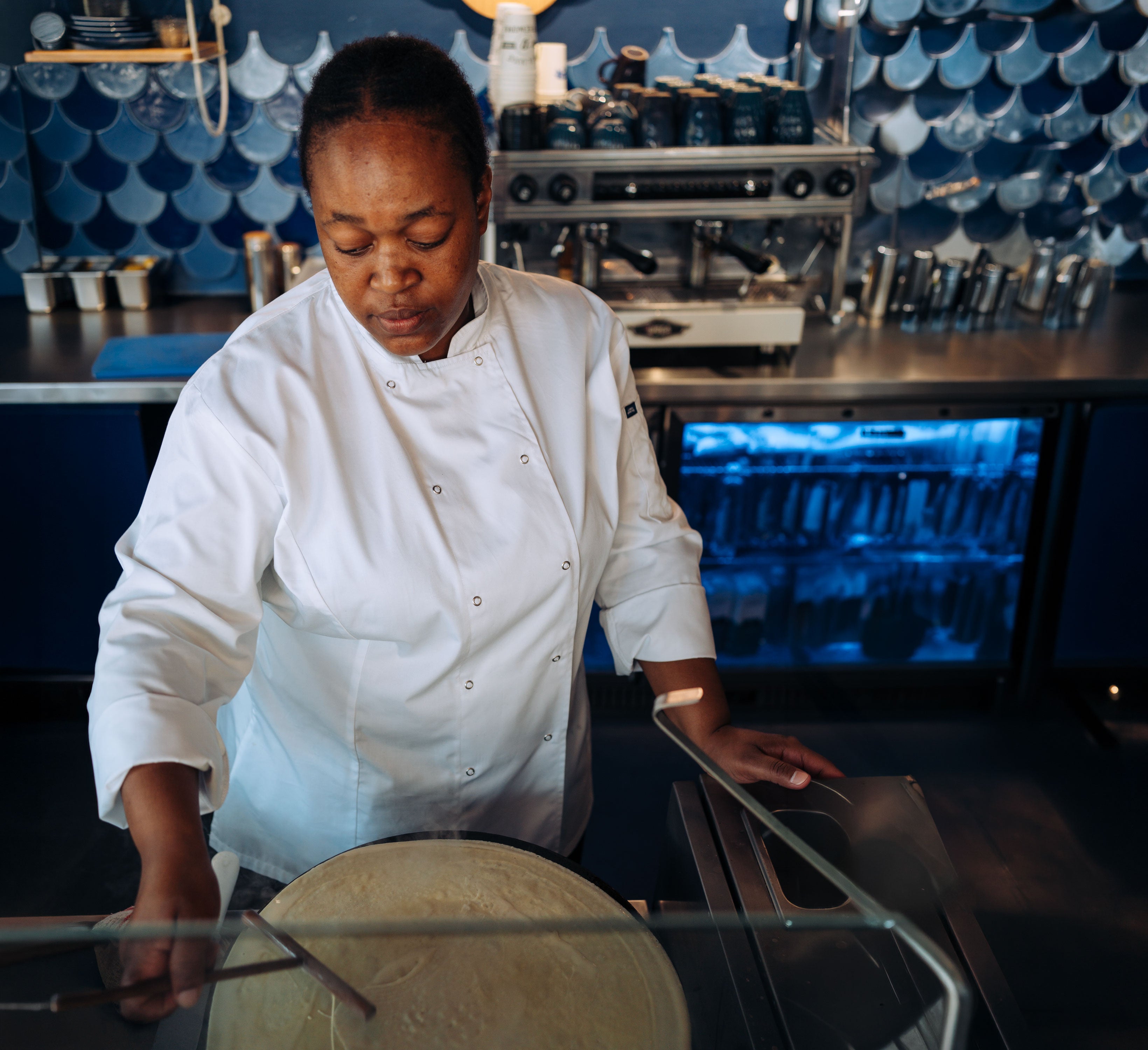 Person in a chef's uniform working in a kitchen setting.