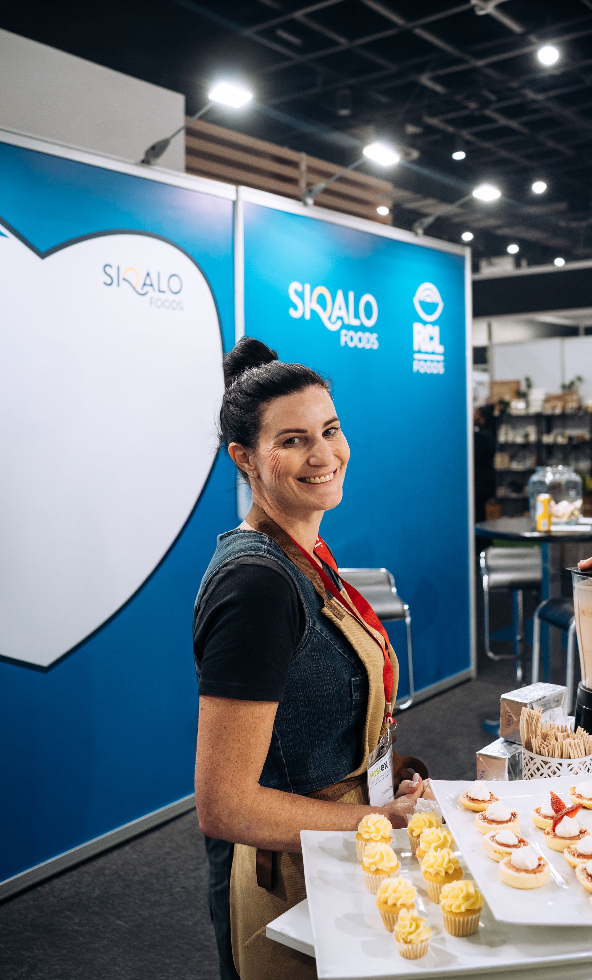 Woman standing in front of a blue backdrop, holding a plate with food.