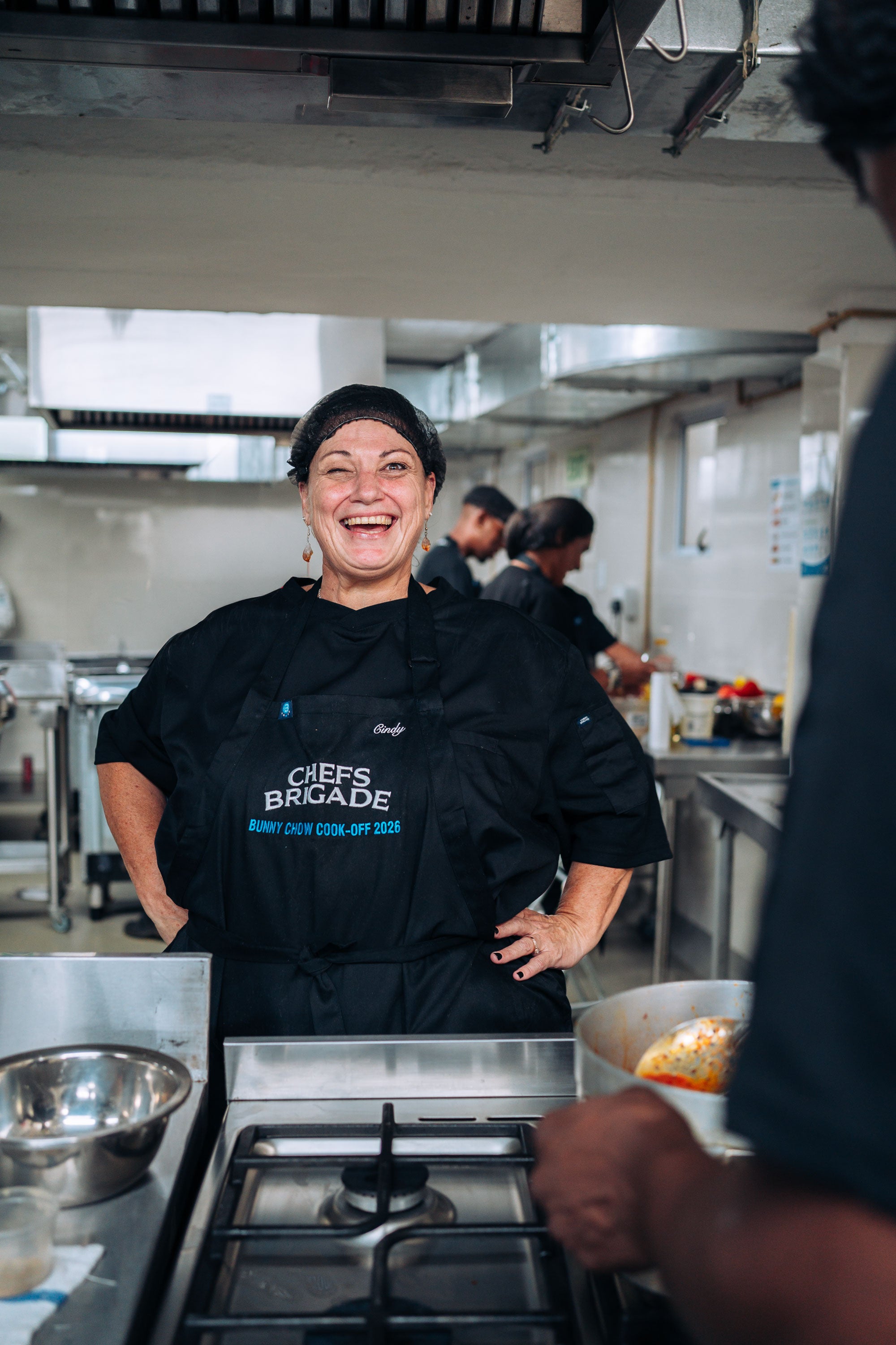 Person wearing a 'Chefs Brigade' apron in a kitchen setting.