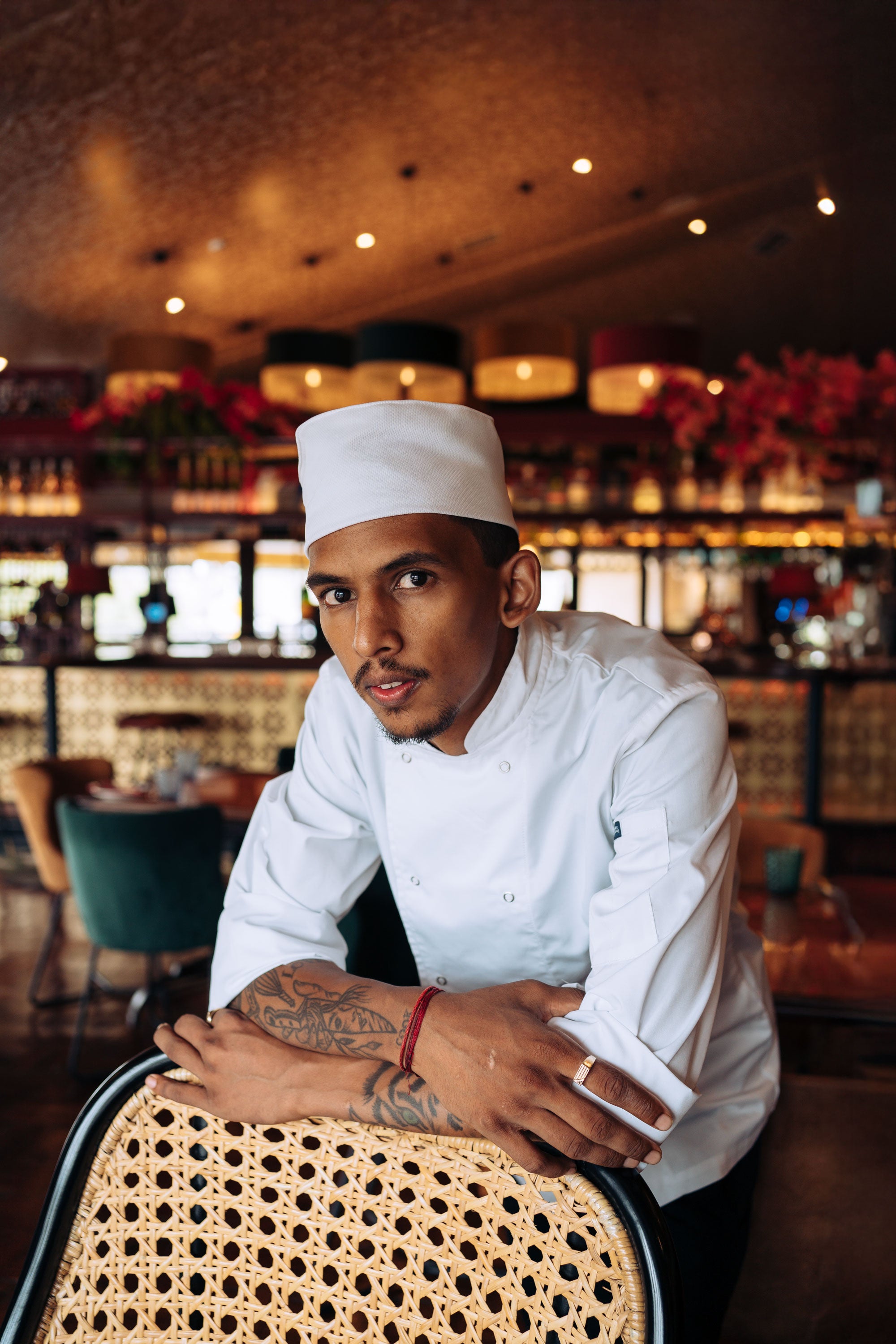 Chef wearing chef headwear in a restaurant setting with a bar in the background