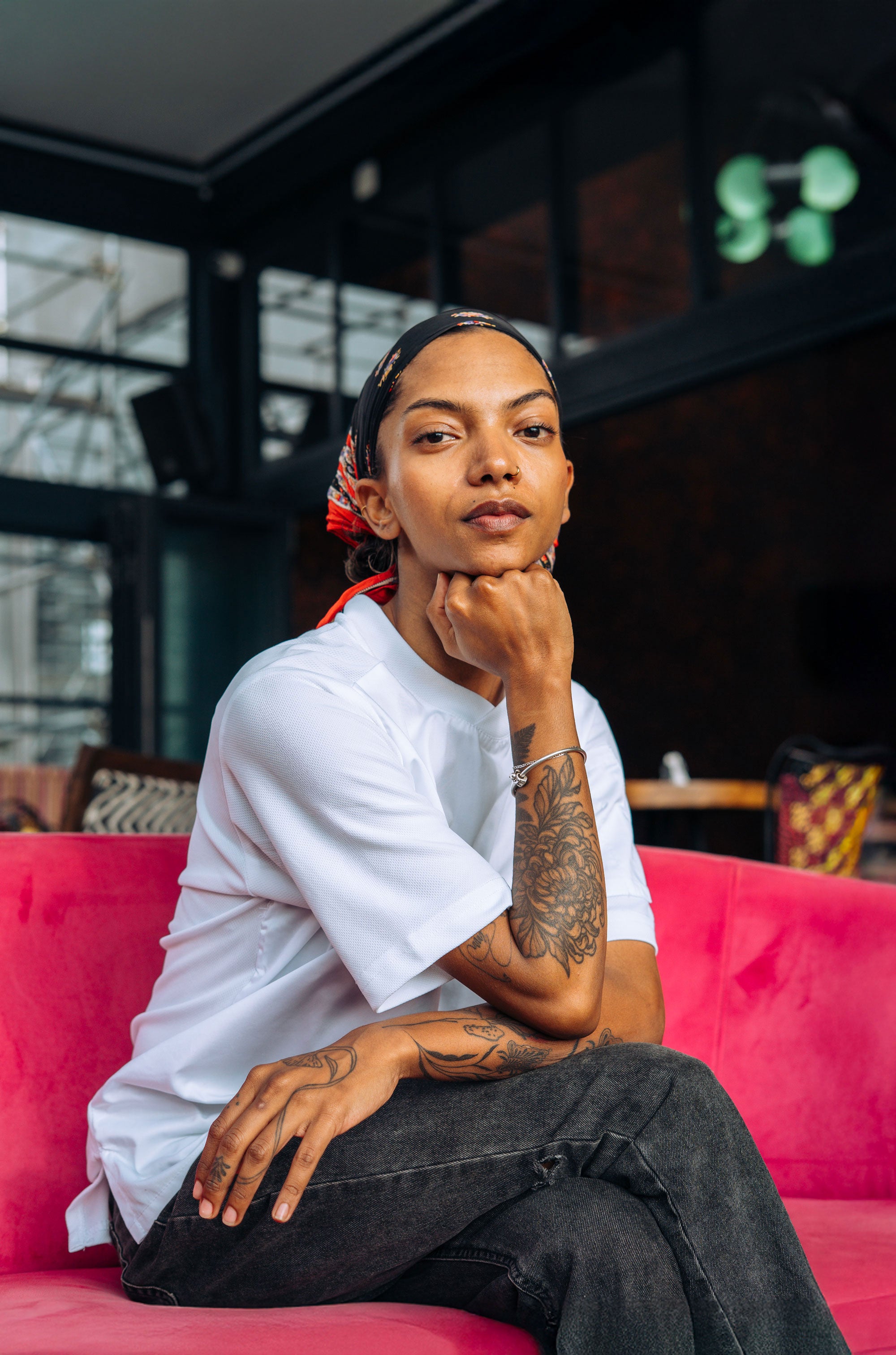 Woman sitting on a pink couch in a chef shirt in a modern indoor setting